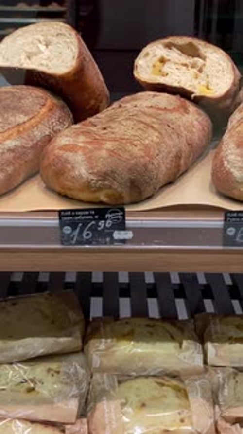 Un assortiment de pain fraîchement cuit se trouve dans une rangée sur une étagère en vente au supermarché