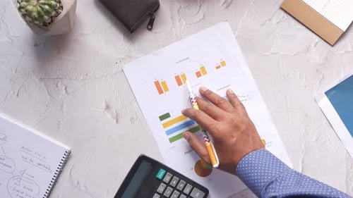 Man Hand with Pen Analyzing Bar Chart on Paper