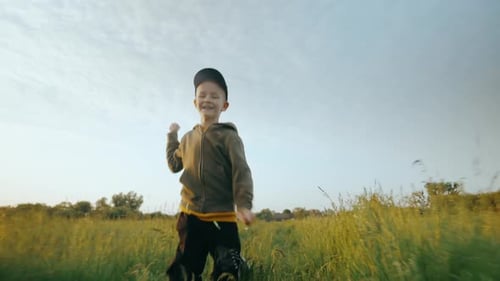 Criança alegre corre ao longo da grama verde