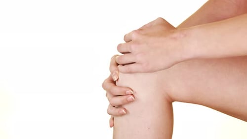 Woman massages her knee due to injury.