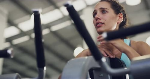 Fit, tired and active female athlete taking a break and resting from an indoor cycling class at gym