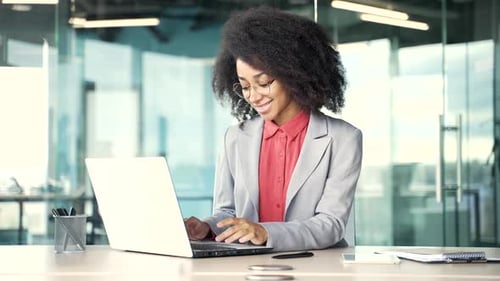 Young Woman Typing on Laptop in Modern Office