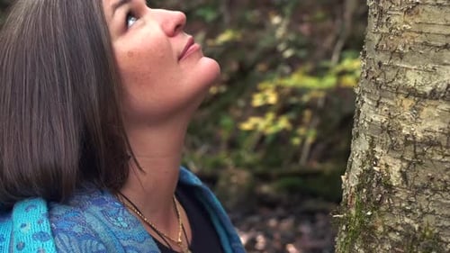 Woman Leans Against Tree in Forested Nature Setting