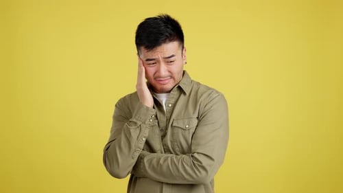 Man Experiencing Pain on a Yellow Background