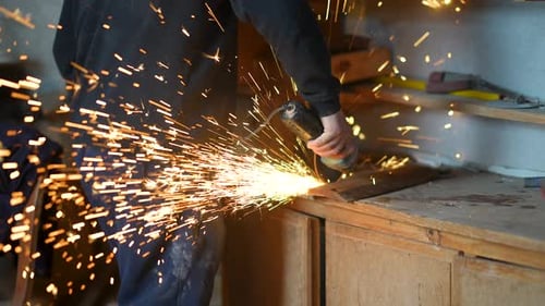 Person Uses Grinder With Flying Sparks in Garage