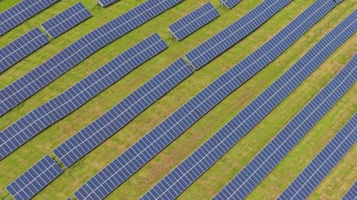 Aerial view of a large solar panel farm with rows of photovoltaic panels generating renewable energy