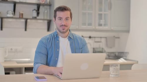 Man Working at Laptop Gives Thumbs Up