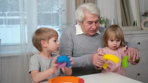 Avô brincando com o neto e a jovem neta, idoso dentro de casa, vovô estudando com
