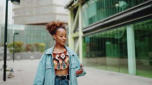 Cute girl walking down the street with phone in her hand