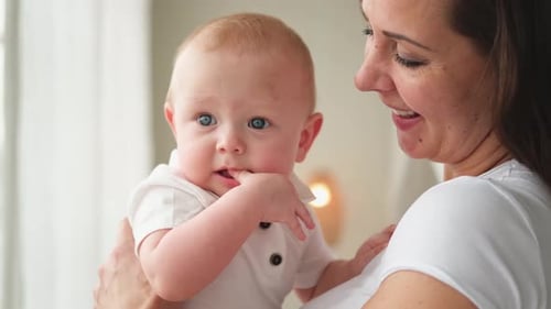 Happy Mother Holding Baby in Arms Indoors