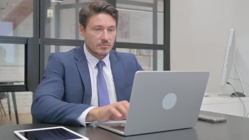Adult Man Working on Laptop in Bright Office