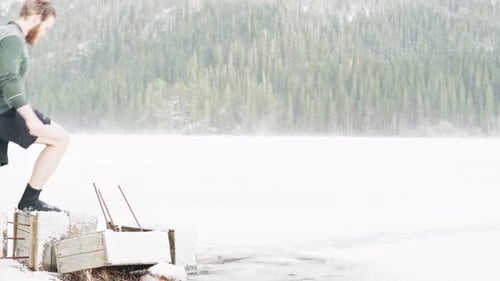 Caucasian Man Wearing Wetsuit Boots Walking At Frozen Lake During Winter Season. - static shot