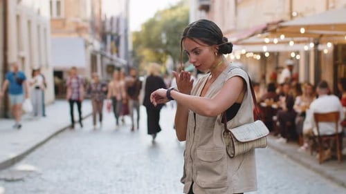 Young Woman Checks Watch on City Street