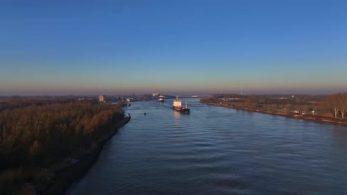 Aerial dolley view of two large vessels sailing over a dutch river during a colorful sunrise