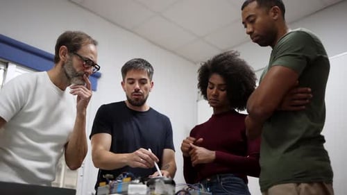 Multi generational and multiracial team of engineers working together on a complex robotics project,