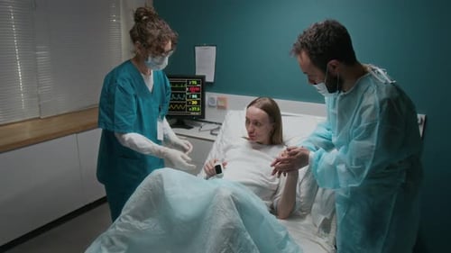 Schwangere Frau bereitet sich auf die Geburt mit Ehemann und Hebamme im Kreißsaal vor
