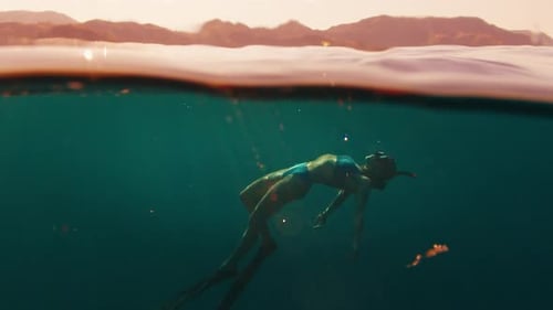 Woman Freediver Swims Underwater in the Sea at Sunset and Relaxes and Floats Beneath the Surface