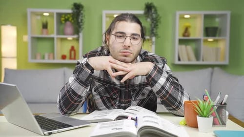 Tired Man Studying at Desk Indoors