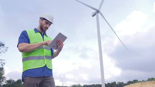 Techniker Ingenieur, der in einer Windkraftanlage arbeitet, oder der Bediener steuert den Wind mithilfe des Tablets