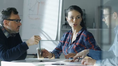 Team of Industrial Engineers Sitting at the Glass Conference Table, Discussing Ongoing Project. On