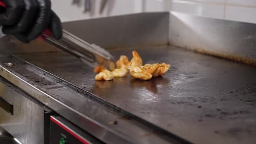 Gloved Hand Grilling Shrimp on Flat Top