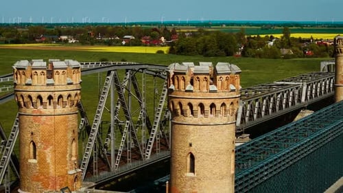 El puente ferroviario que cruza entre torres redondas de ladrillo con armazón de acero se extiende sobre el puente ferroviario de hierro