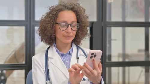 Female Doctor Using Smartphone in Hospital Setting