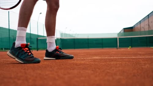 close-up professional player coach on outdoor tennis court practices strokes with racket and ball