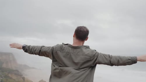 Man Overlooking Ocean From Cliff Embracing Freedom