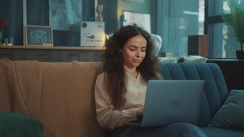 Woman Using Laptop on Sofa in Cozy Home
