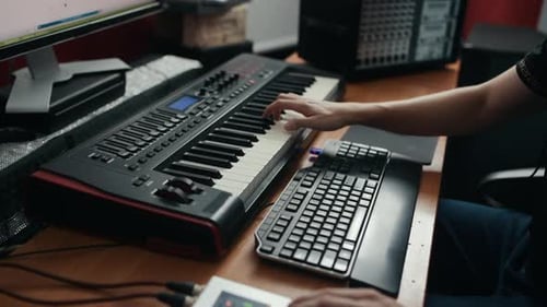 Close up view of man's hands that playing on midi keyboard in the studio