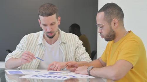 Young Men Reviewing Charts at Workplace