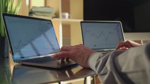 A trader walks up to two laptops displaying charts of the bitcoin exchange and starts working. Close