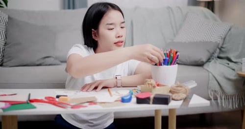 Young Woman Drawing at Table with Art Supplies