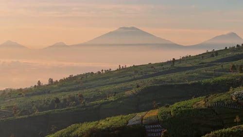 Drone footage capturing majestic mountain silhouettes rising above misty valleys during morning