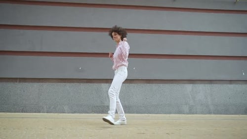 Woman with Afro dancing on a city sidewalk