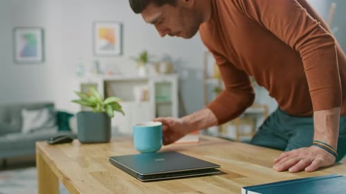 Man Opens Laptop and Starts Typing at Table