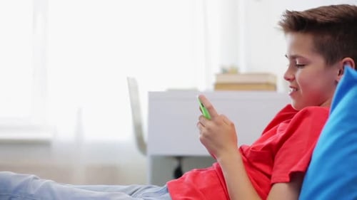Teen relaxes, using smartphone on couch