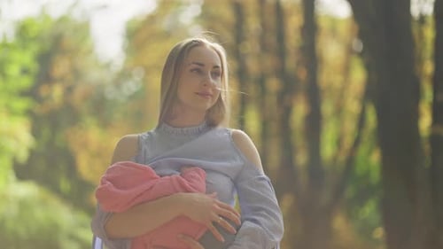 Mother Feeds Her Child in Autumn Forest Concept of Breastfeeding