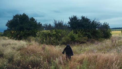 Dark Robed Figure with Mask Standing in Field