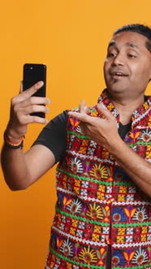 Vertical Video Joyous Man Greeting Friend Over Online Videocall on Cellphone Studio Background