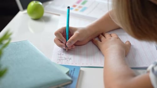 Middle School Smiling Student Boy Sitting at Desk Studying Writing Book Homework and Tablet at Class