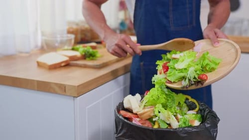 Close up of a kitchen trash bin filled with fresh food waste in house.
