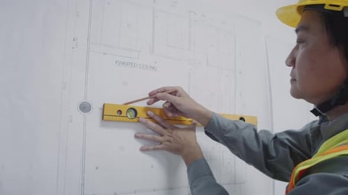 Asiatischer Vorarbeiter verwendet Construction Level beim Bearbeiten des Blueprints