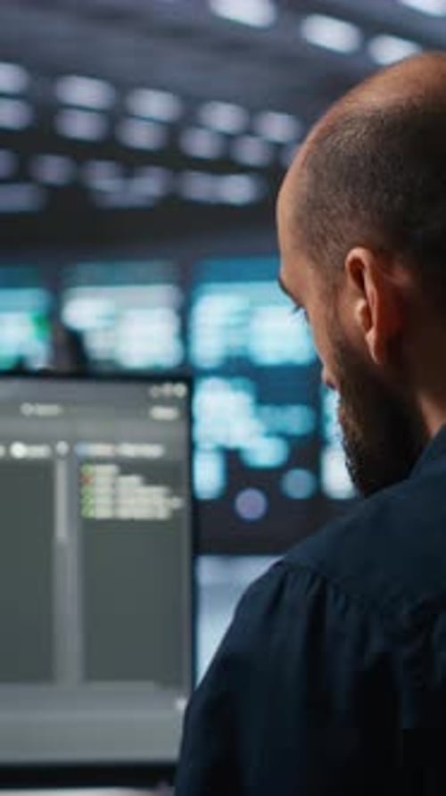 Administrateur Vidéo vertical exécutant un script de codage sur un écran d'ordinateur dans un centre de données de haute technologie