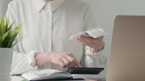 Woman Calculates Finances with Receipts at Desk