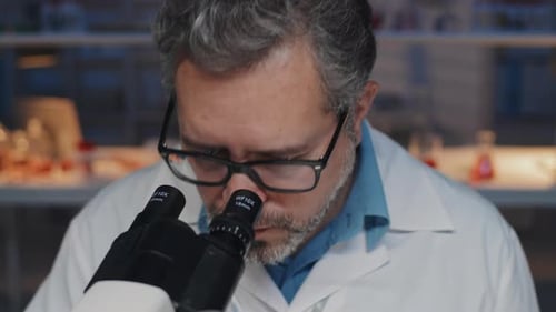 Scientist Looking Through Microscope in a Lab