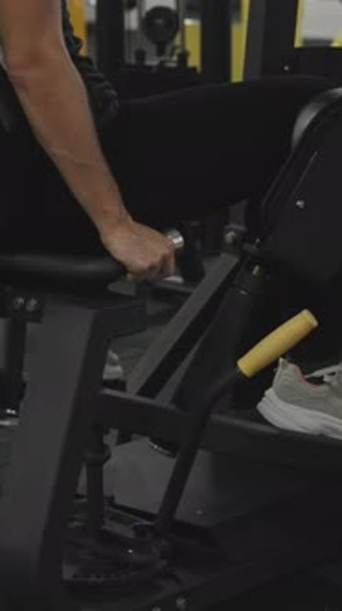 Vertical video. Woman in Black Pants in the Gym, Doing Leg Abductions on a Sports Machine.