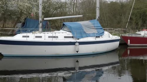 Small sailboats moored on narrow rural countryside canal harbour