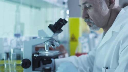 Der leitende Wissenschaftler arbeitet mit Kollegen in einem Labor mit einem Mikroskop.